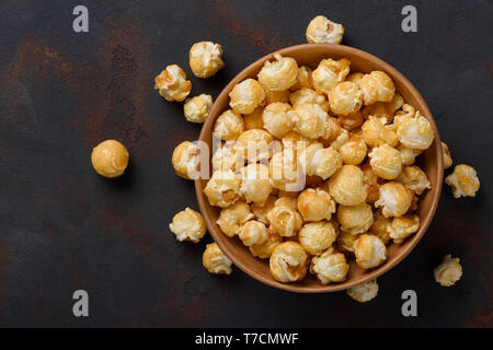 Karamell Popcorn in der Schüssel auf dunklen Tisch Hintergrund Stockfoto