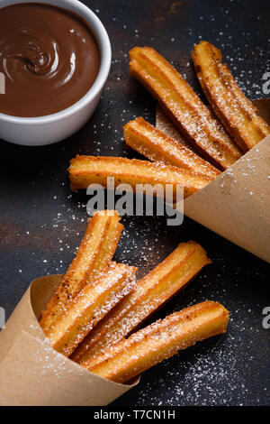 Churros mit Zucker, Zimt und Schokolade Soße dip auf dunklem Hintergrund Stockfoto