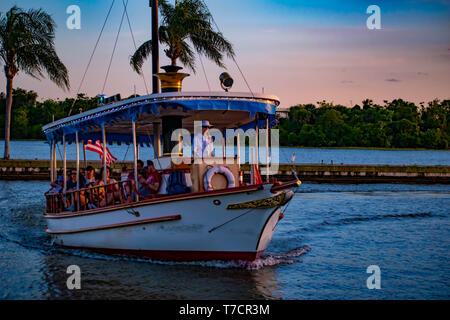 Orlando, Florida. April 23, 2019. Taxi Boot an der Küste und Palmen auf bunten Sonnenuntergang Hintergrund bei der Walt Disney World Bereich ankommen. Stockfoto