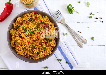 Köstliche Bulgur mit Gemüse, Fleisch und Gruene haben sich auf eine weiße Holztisch. Diätetisches Menü. Die richtige Ernährung. Ansicht von oben. Stockfoto