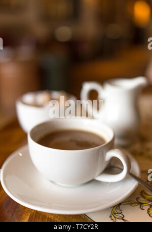 Tasse Kaffee mit Zuckerdose und Milchkännchen in Café mit verschwommenen Hintergrund Stockfoto