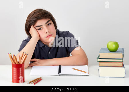 Unglücklich und deprimiert kaukasischen student Gefühl ist verwirrt und verärgert, während seine Hausaufgaben Stockfoto