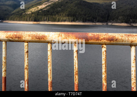 Rostige Geländer gegen Mountain Lake Stockfoto