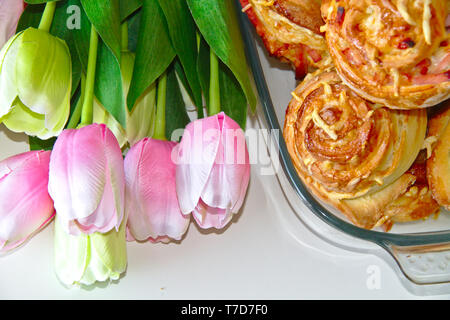 Weltbesten pinwheels mit köstlichen Schinken und Käse. Mit rosa und weißen Tulpen umgeben. Stockfoto