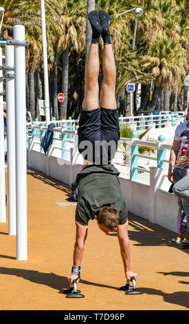 CANNES, Frankreich - April 2019: Person, einen handstand auf ein Fitnessbereich im Freien an der Promenade in Cannes. Stockfoto