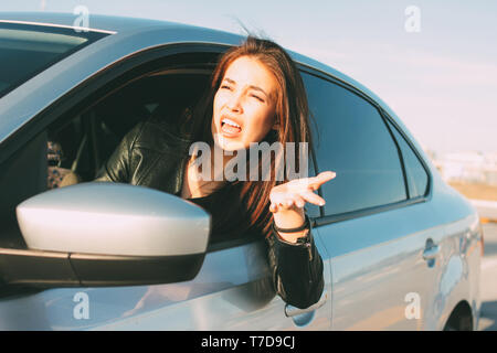 Schöne Brünette lange Haare wütende junge asiatische Frau fahren und Schreien im Auto. Stockfoto