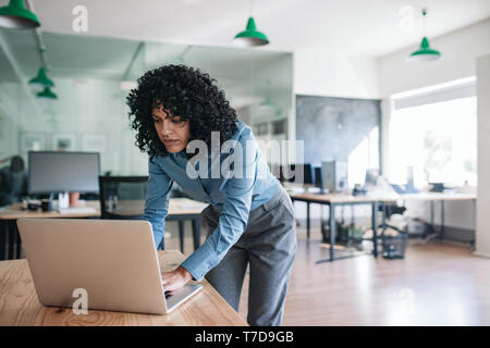 Junge Unternehmerin über ihr Büro Schreibtisch mit einem Laptop Stockfoto