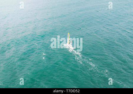 Extreme mann Athlet schwimmt auf der Wind Surf auf der sea wave gegen das blaue Meer und den Horizont. Extreme Wassersport. Bewegung der Red Sail auf der Stockfoto