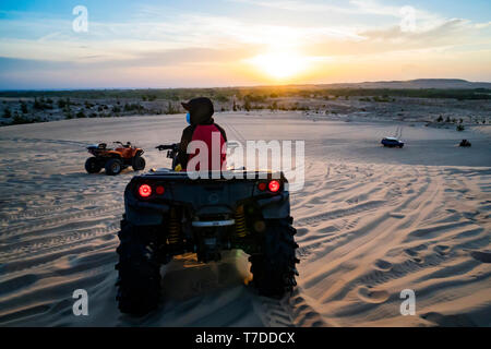 Junger Mann in Safari Reise durch die Ägyptische Wüste fahren ATV bei Sonnenuntergang. Quad Safari in der Wüste in der Nähe von Hurghada, Ägypten Stockfoto