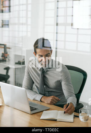 Lächeln, Geschäftsmann, Sitzen bei der Arbeit schreiben Ideen in einem Notebook Stockfoto