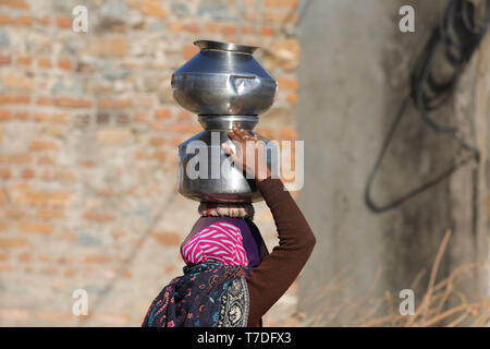 Frau schwer tragen, Wasser Schüssel auf dem Kopf eine "Lange, die Straße zu Ihrer Startseite Stockfoto