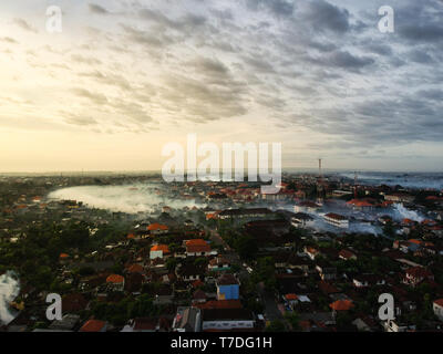 Luftaufnahme von Bergen in Bali von Stadt Denpasar mit Rauch und gelbe Markierung in den bewölkten Himmel Stockfoto