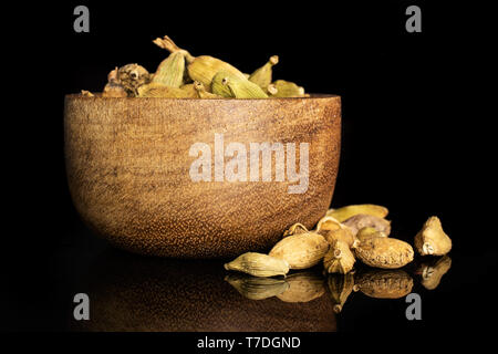 Menge ganze wahre Cardamom pod in der Nähe von und in eine hölzerne Schüssel auf schwarzem Glas isoliert Stockfoto