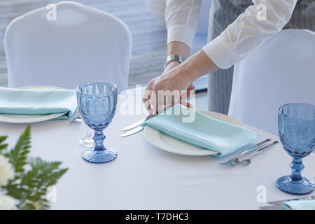 Hochzeitstisch einrichten. Die Kellner in einem grauen Anzug und weißes Hemd dient die Tabelle Stockfoto