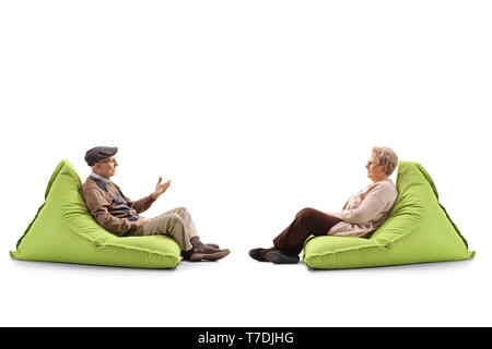 Volle Länge Profil geschossen von einem älteren Ehepaar sitzt auf einem Bean Bag Sessel und Sprechen auf weißem Hintergrund Stockfoto