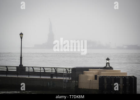 Hudson River Docks unter dem Regen mit Blick auf die Freiheitsstatue aus dem Herzen der Wall Street in Manhattan, New York Stockfoto