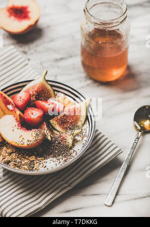 Gesund Sommer Frühstück. Griechischer Joghurt Müsli Schüssel mit Erdbeeren, Feigen, Pfirsich, Chia Samen und Honig mit weißem Marmor Hintergrund. Vegetarisch, d Stockfoto