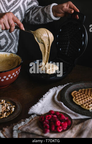 Frau ist Gießen Teig auf WAFFELEISEN Stockfoto