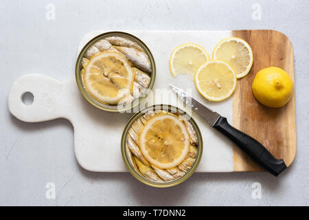 Zwei Dosen Sardinen in Öl mit Scheiben frischer Zitrone. Stockfoto