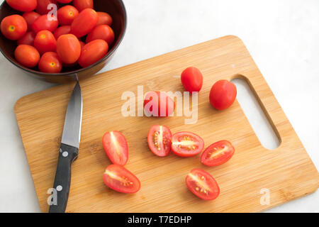 Slicing Trauben Tomaten auf einem Schneidebrett Stockfoto