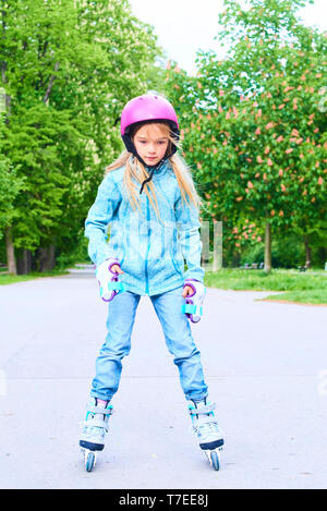 Süßes kleines Kind Mädchen lernen, Roller Skate auf schönen Sommertag in einem Park. Kind tragen Schutzhelm Roller Skating Fahrt im Freien genießen. Stockfoto