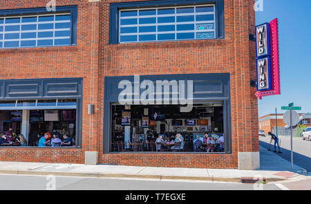 JOHNSON CITY, TN, USA -4/27/19: Kunden gesehen Speisen durch die Fenster des wilden Flügel Restaurant, während ein Mitarbeiter der Aufkantung außerhalb fegt. Stockfoto