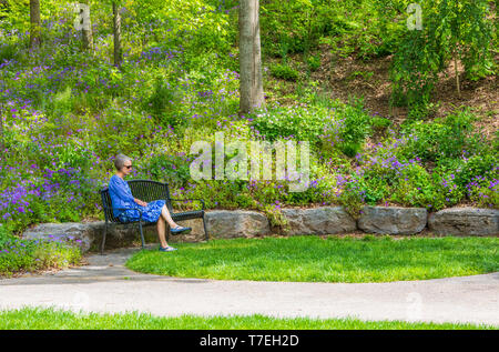 Erwin, TN, USA -4/28/19: attraktive Frau meditieren auf einer Bank in einem schönen Park an einem Frühlingstag. Stockfoto