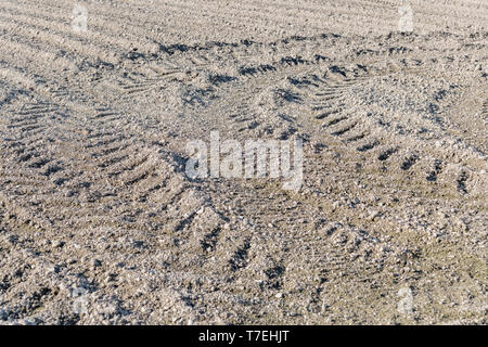 Getrocknete Erde in einem GEPFLÜGTEN/gepflügten Feldes, mit Furchen/Reifenspuren sowie der Traktor rig gedreht hat. Gepflügten Boden Textur, gebogene Gleise, gepflügte Erde. Stockfoto