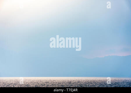 Hazy Abendlicht glitzert auf der Oberfläche des Wassers auf - Atitlan See, Guatemala Stockfoto
