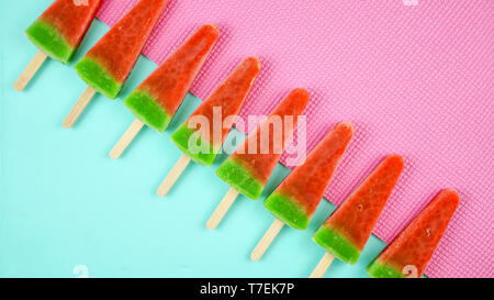 Wassermelone aromatisiert Sommer Thema Eis Eis am Stiel auf Rosa und blauem Hintergrund. Stockfoto