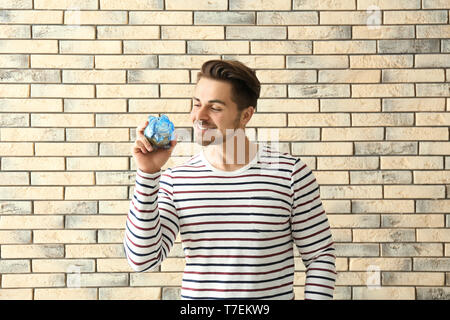 Junger Mann mit Sparschwein auf Stein Hintergrund. Einsparungen geld Konzept Stockfoto