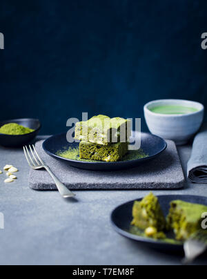 Matcha grüner Tee Kuchen, Bars, Brownie mit weißer Schokolade auf einem Teller. Grauen Stein Hintergrund. Kopieren Sie Platz. Stockfoto