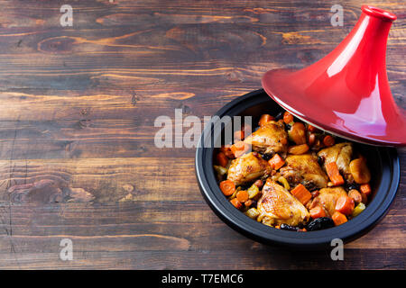 Tajine mit gekochtem Hühnerfleisch und Gemüse. Hölzerne Hintergrund. Kopieren Sie Raum. Stockfoto