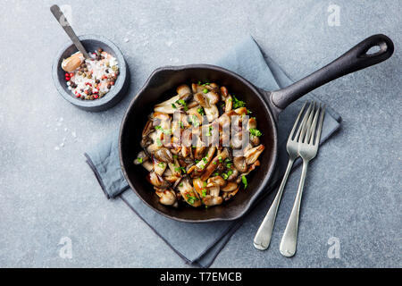 Gebratene Pilze mit frischen Kräutern in schwarzen gusseisernen Pfanne. Ansicht von oben. Stockfoto