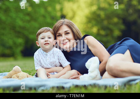 Mutter mit Kind sitzen auf Gras im Park Stockfoto