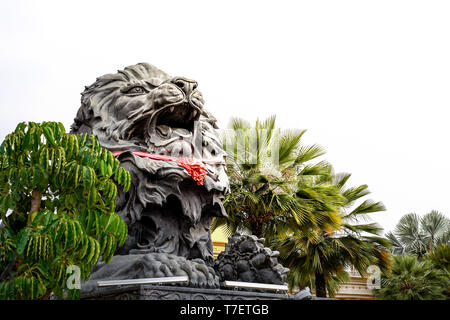 Bis big black lion Statue mit roten Schal sitzen vor Gebäude schließen., Laos. Stockfoto