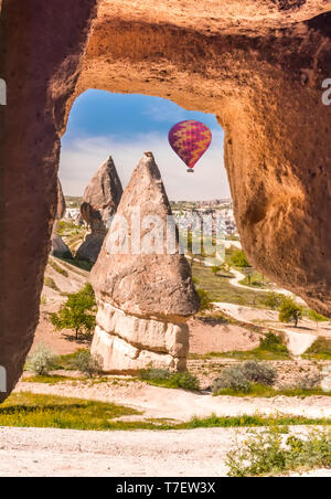 Hand geschnitzten Arch im Kalkstein im Nationalpark Göreme in Kappadokien. Bunte Heißluftballons fliegt im blauen Himmel in Kapadokya, Türkei Stockfoto