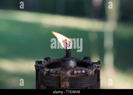 Nahaufnahme, Taschenlampe und Feuer im Garten mit grün Unschärfe im Hintergrund. Stockfoto