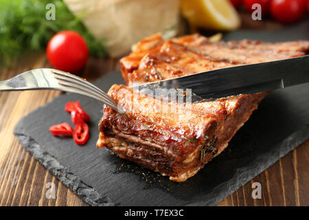 Schneiden von köstliche gegrillte Rippen auf schiefer Platte Stockfoto