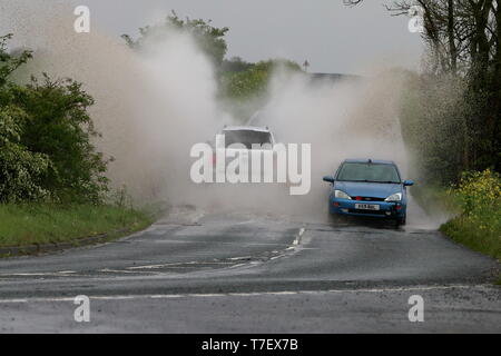 SUV-Spritzer am kommenden Auto, wie es durch eine große Pfütze von Wasser nach starkem Regen geht Stockfoto