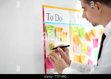 Mann schreiben auf Kurznotiz angefügt Aufgabe in seinem Amt zu Scrum Stockfoto