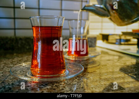 Gießen türkischer Tee in den traditionellen dünnen Bauch Glas in der Küche Nähe zu sehen. Stockfoto