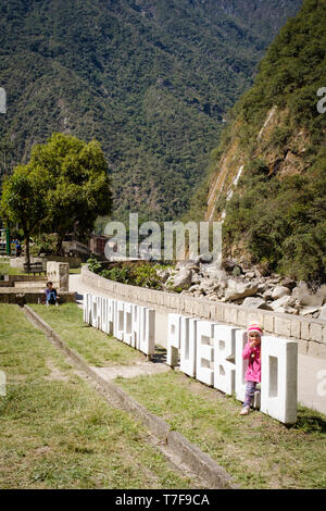 Kleine Mädchen in rosa versteckt sich in der Machu Picchu Pueblo (auch als Aguas Calientes) Schild, Peru bekannt Stockfoto