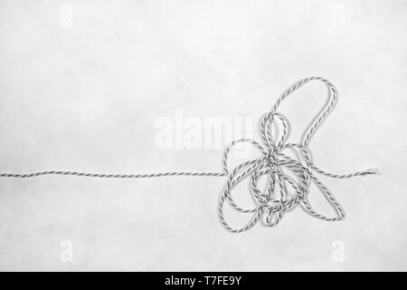 Ein verworrenes Stück Schnur heraus auf einem weißen Hintergrund gelegt. Schwarz-weiß-Fotografie. Stockfoto