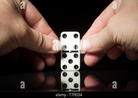 Männlichen Händen domino Achsschenkel auf eine schwarze Fläche. Stockfoto