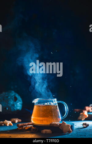 Teekanne aus Glas mit aufsteigenden Dampf und sternförmige Cookies auf einem dunklen Hintergrund mit kopieren. Astrologie themed Stockfoto