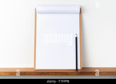 Designkonzept - Blick von oben auf die weißen A4-Papier umgedreht auf braun Zwischenablage auf weißem Hintergrund und Bücherregal für mockup. echte Fotos und nicht für 3D-Rendering Stockfoto