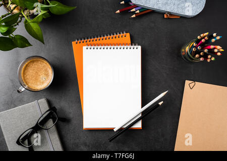 Designkonzept - Ansicht von oben kopieren Raum mit orangefarbenen Spirale notebook, Topfpflanze, Gläser, Kaffee, Bleistift auf schwarzen Hintergrund für mockup Stockfoto