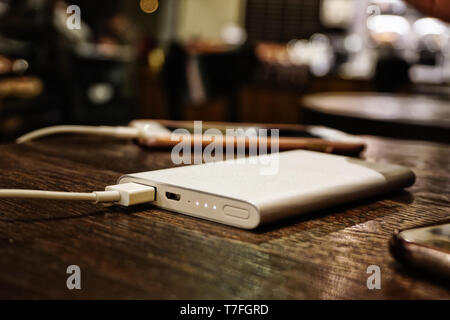 Powerbank laden smartphone Nahaufnahme auf hölzernen Hintergrund Stockfoto