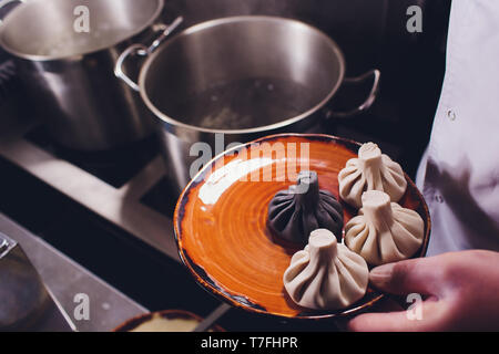 Khinkali oder Knödel sind in Abgekochtem Wasser auf dem Herd in einem Topf gekocht durch Dampf. Kochen. Schwarze Farbe. Stockfoto